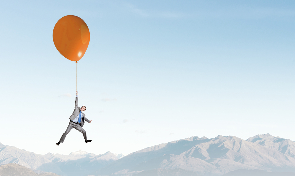 Young successful businessman flies on colorful balloon